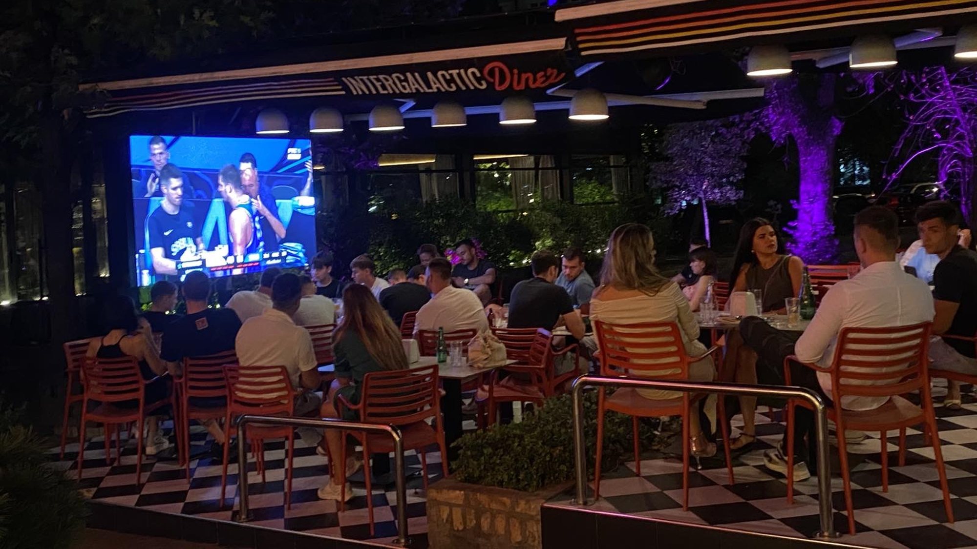 Bašta sa velikim LED ekranom i gostima uveče — Intergalactic Diner Novi Beograd